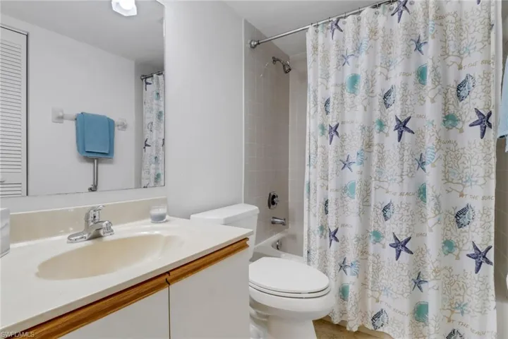 Bathroom with toilet, vanity, and shower / bath combo with shower curtain