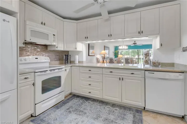 Kitchen with white cabinets, a sink, a ceiling fan, and white appliances