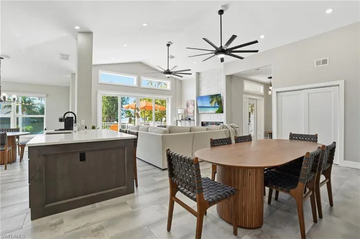 Dining area featuring healthy amount of natural light, lofted ceiling, a ceiling fan, a chandelier, and a fireplace - Virtually Edited Image