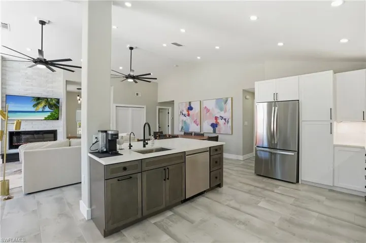 Kitchen with a fireplace, stainless steel appliances, open floor plan, two tone cabinetry, and recessed lighting - Virtually Edited Image