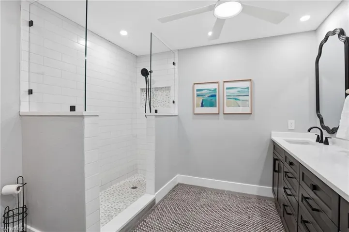Full bathroom with walk in shower, vanity, recessed lighting, and dark tile patterned floors - Virtually Edited Image