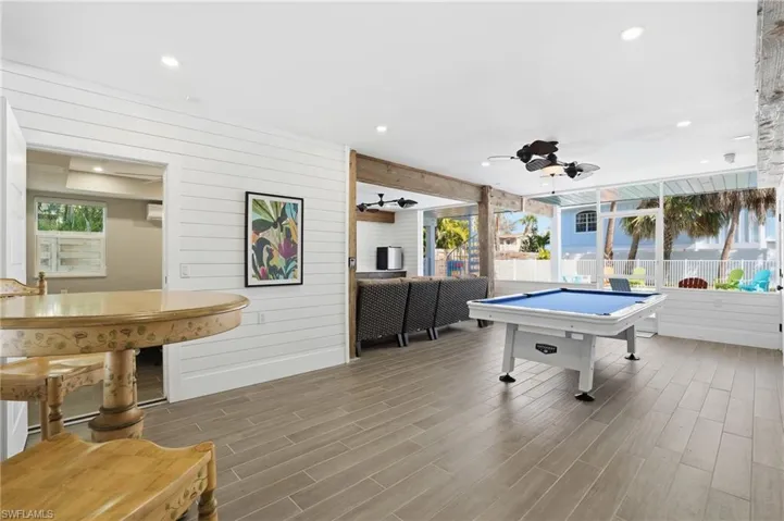Rec room with wood tiled floors, wood walls, recessed lighting, ceiling fan, and billiards - Virtually Edited Image