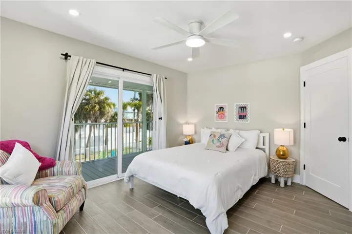 Bedroom with wood finish floors, access to exterior, recessed lighting, and a ceiling fan - Virtually Edited Image