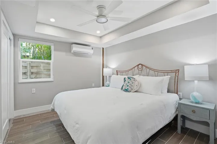 Bedroom with wood finish floors, a raised ceiling, recessed lighting, and ceiling fan - Virtually Edited Image