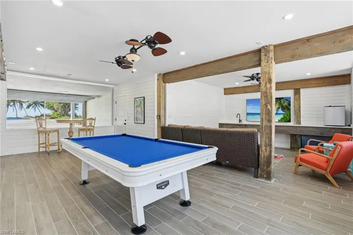 Rec room with wooden walls, a ceiling fan, wood tiled floors, billiards, and recessed lighting - Virtually Edited Image