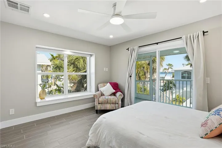 Bedroom featuring wood tiled floors, recessed lighting, a ceiling fan, and access to exterior - Virtually Edited Image