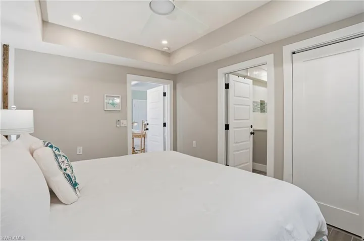Bedroom with a raised ceiling, a ceiling fan, recessed lighting, and wood finished floors - Virtually Edited Image