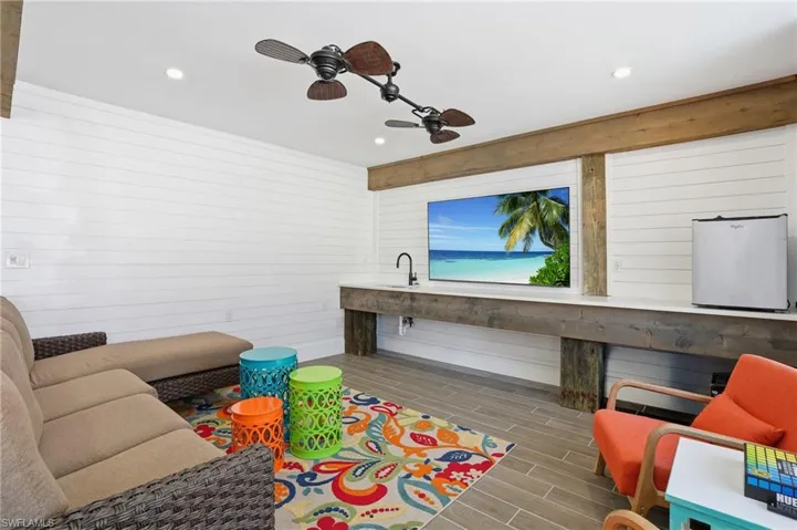 Living room with wood finish floors, ceiling fan, wood walls, and recessed lighting - Virtually Edited Image