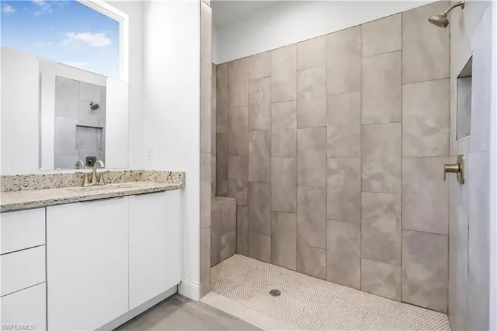 Full bath featuring tiled shower and vanity