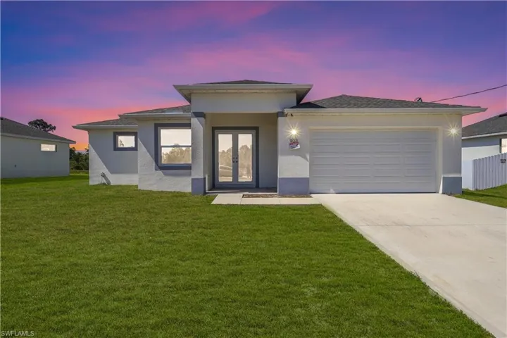 Prairie-style home with stucco siding, driveway, a front lawn, and a garage