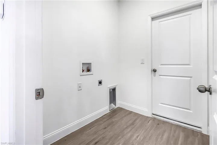 Washroom featuring hookup for an electric dryer, washer hookup, baseboards, wood finished floors, and laundry area