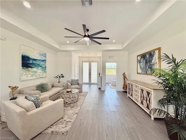 Living area with visible vents, french doors, recessed lighting, and a tray ceiling