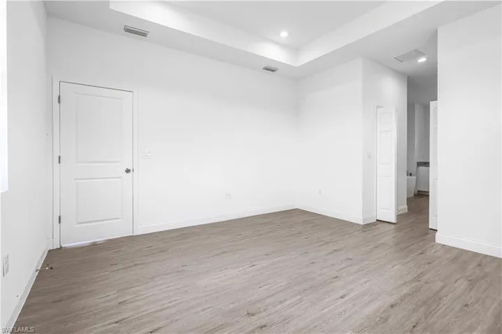 Unfurnished room with recessed lighting, visible vents, wood finished floors, and a tray ceiling