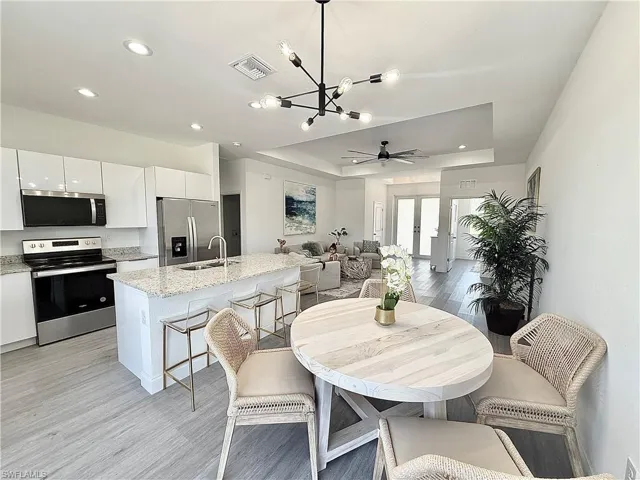 Dining space featuring recessed lighting, a chandelier, light wood-style floors, a tray ceiling, and visible vents
