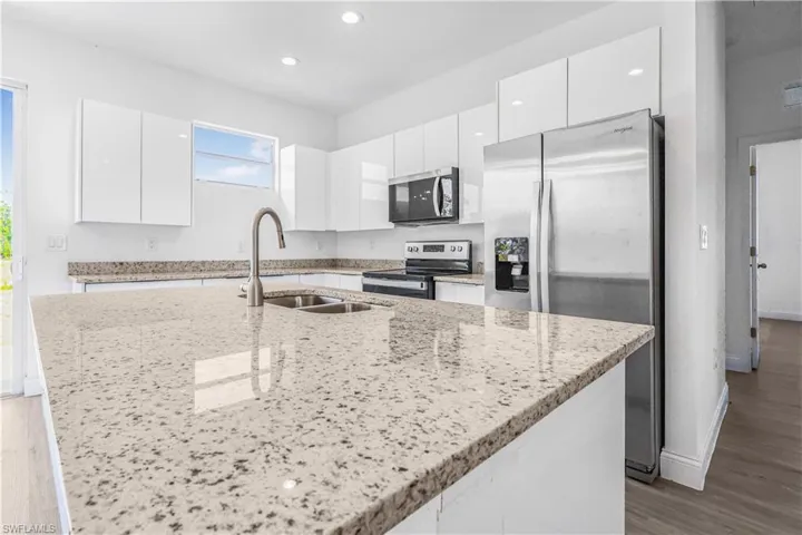 Kitchen with modern cabinets, a sink, stainless steel appliances, white cabinets, and an island with sink