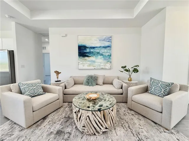 Living room featuring visible vents, light wood-type flooring, and a raised ceiling