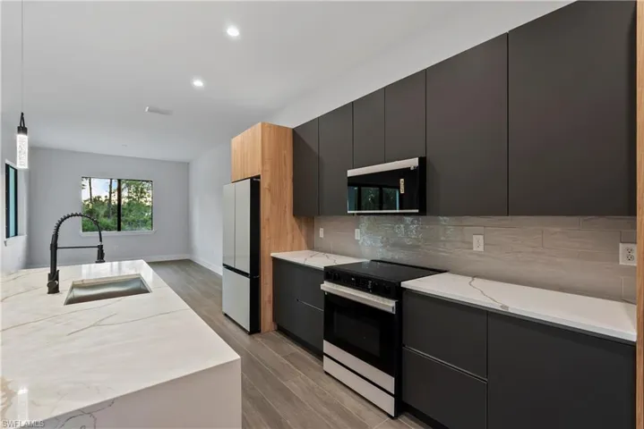 Modern kitchen featuring a waterfall island with an undermount sink and matte black gooseneck faucet