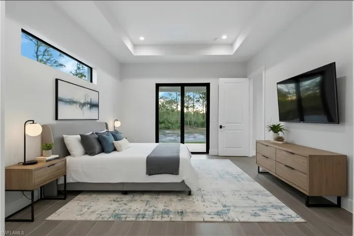 Spacious room featuring a tray ceiling with recessed lighting, high windows, a large glass door leading to the exterior, and wood-finish flooring