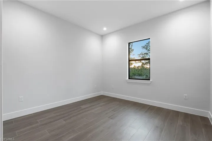 Naturally lit room featuring wood-finish flooring, white baseboards, and recessed lighting