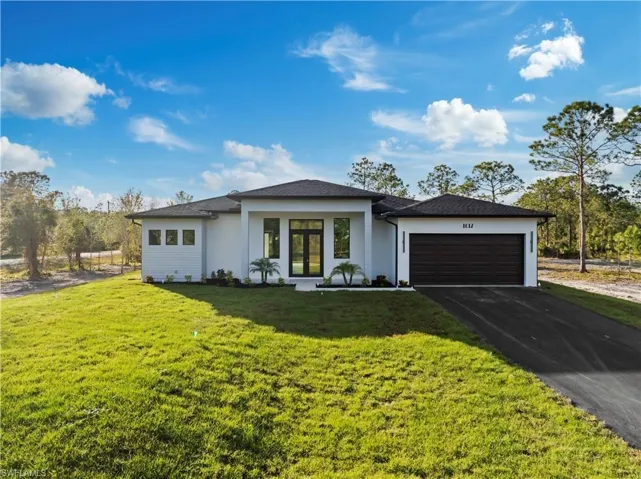 Modern white stucco exterior with dark trim accents, featuring a two-car garage and a paved driveway