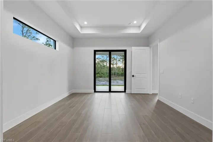 Interior space featuring wood-finish flooring, a tray ceiling with recessed lighting, and a transom window
