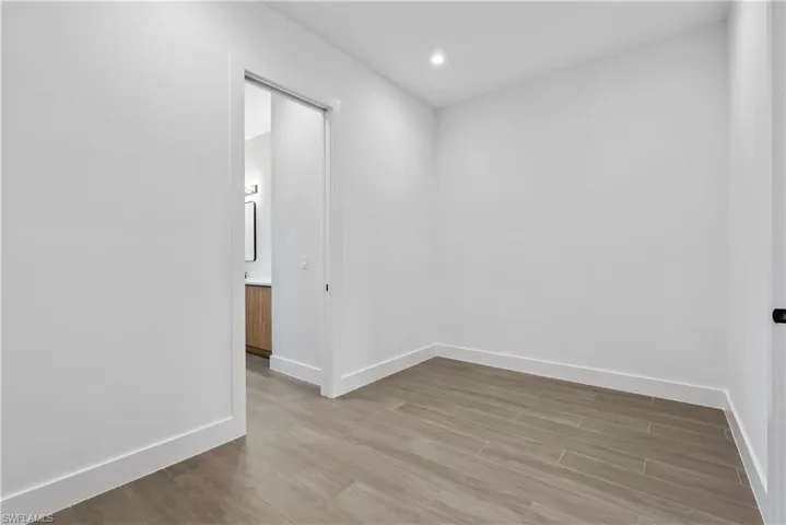 Neutral wall tones with tile flooring, featuring a recessed ceiling light and a pocket door leading to an en-suite with a vanity and mirror