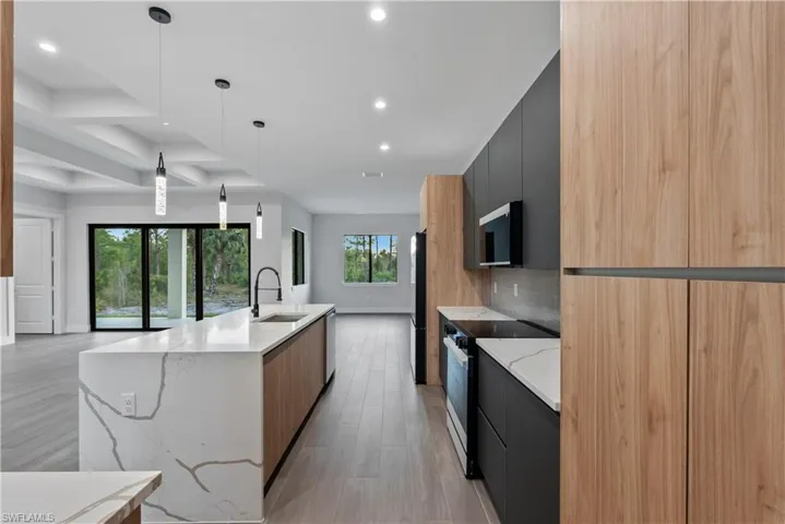 Modern kitchen featuring a waterfall island with a white countertop, contrasting wood-finish and dark cabinetry, and integrated stainless steel appliances
