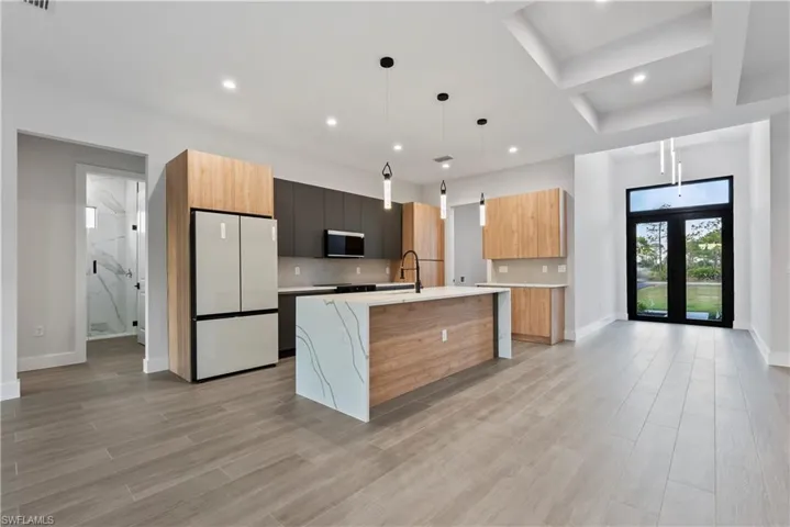 Open-concept kitchen with a waterfall island, integrated appliances, wood-finish and dark flat-panel cabinetry, and pendant lighting