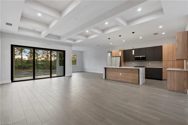 Open-concept living space featuring wood-finish flooring, a coffered ceiling, and recessed lighting