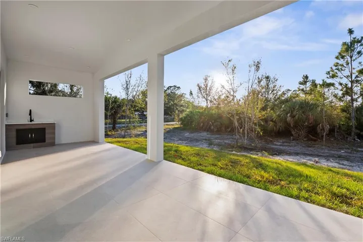 Expansive covered patio featuring large format tile flooring, a built-in outdoor kitchen with a sink, and a horizontal transom window