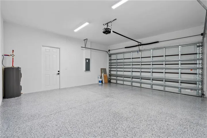 Spacious two-car garage featuring a speckled epoxy floor coating, white interior walls, and an automatic garage door opener