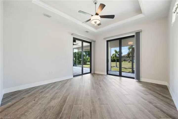 Primary Bedroom with Volume Ceiling with Tray Accent & 2 Sliders to the Screened Lanai