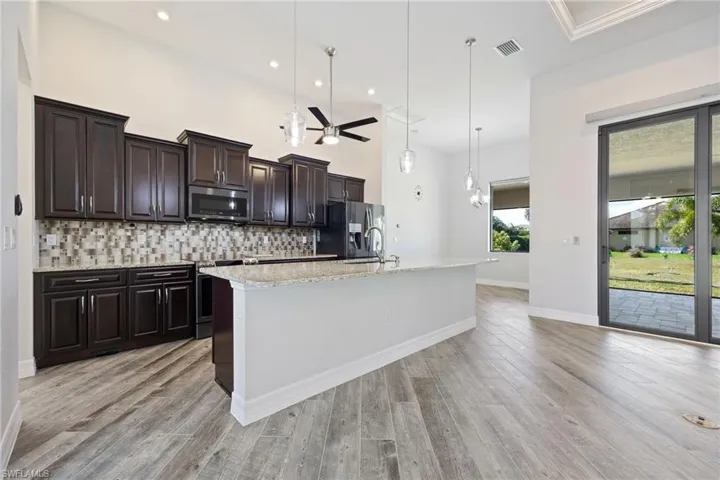 Open Kitchen with Attractive Wood Cabinetry, a Large Island, Granite Countertops & Stainless Steel Appliances
