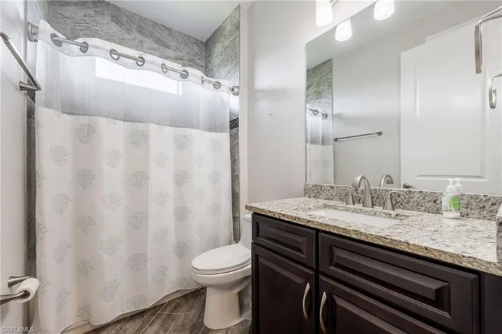Guest Bathroom with a Tub/Shower Combination, Wood Vanity & Granite Countertop