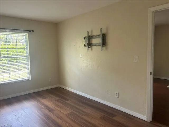 Primary bedroom with baseboards and dark wood-style floors