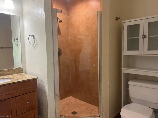 Main Bathroom with a stall shower, a textured wall, and a vanity