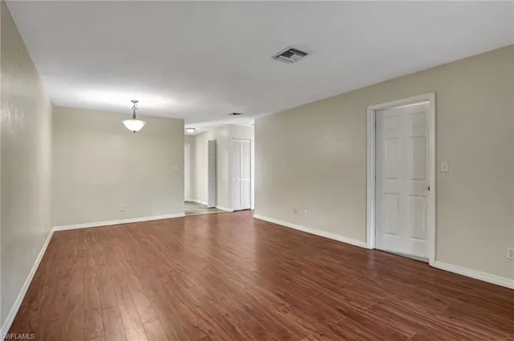 Unfurnished room featuring dark wood-style floors and baseboards