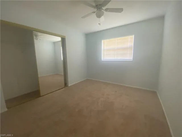 Unfurnished bedroom featuring light colored carpet, ceiling fan, and a closet
