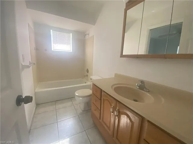 Full bathroom with tile patterned flooring, toilet, shower / washtub combination, and vanity