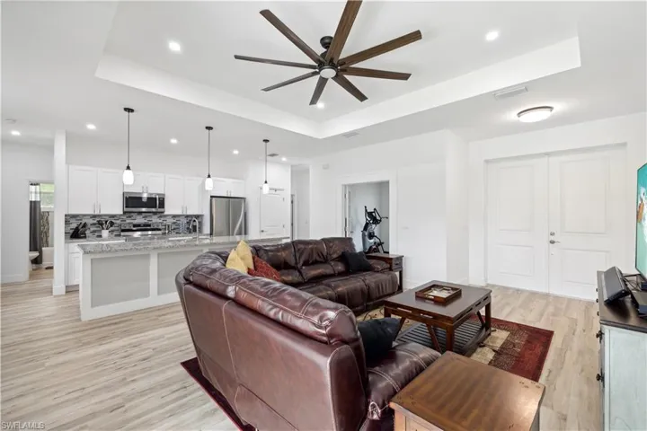 Living room featuring light hardwood / wood-style floors, ceiling fan, a raised ceiling, and sink