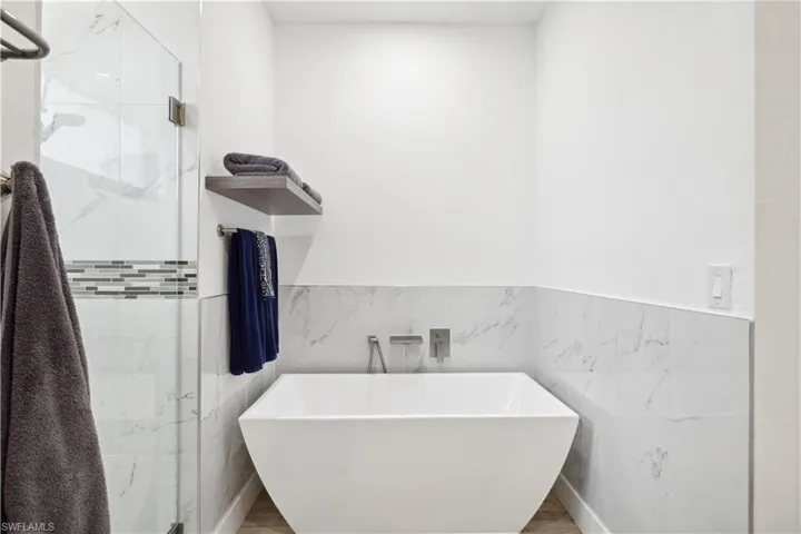 Bathroom featuring plus walk in shower and tile walls