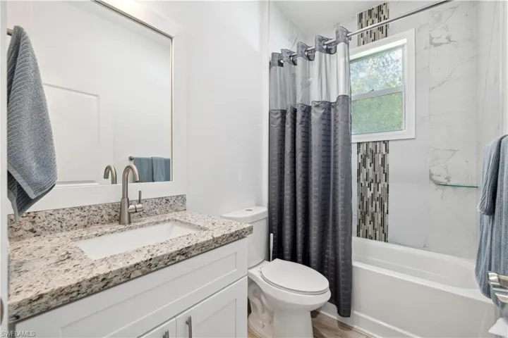 Full bathroom featuring vanity, toilet, shower / bathtub combination with curtain, and hardwood / wood-style flooring