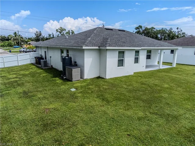 Rear view of house with a yard, a patio, and central air condition unit
