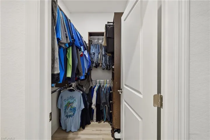 Walk in closet with wood-type flooring