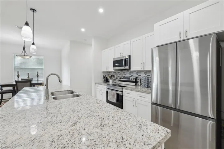 Kitchen featuring pendant lighting, sink, white cabinetry, appliances with stainless steel finishes, and decorative backsplash