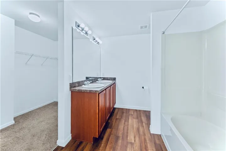 Full bathroom featuring visible vents, baseboards, a sink, and wood finished floors
