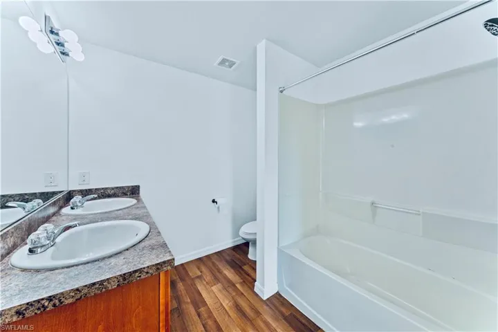 Full bath featuring toilet, wood finished floors, a sink, and visible vents