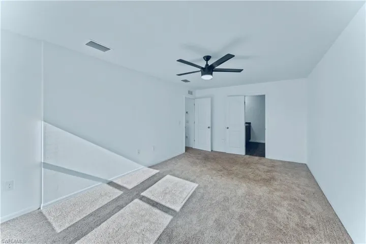 Unfurnished bedroom with ceiling fan, carpet flooring, baseboards, and visible vents