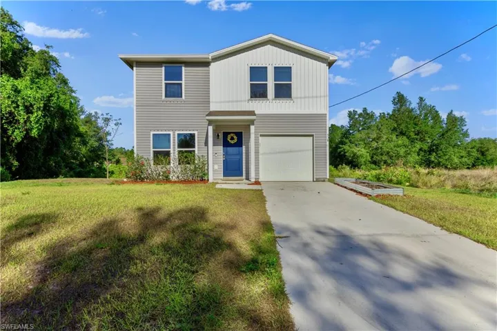 Traditional home with a front lawn, a garage, and concrete driveway