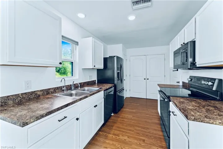 Kitchen with visible vents, a sink, black appliances, and dark countertops